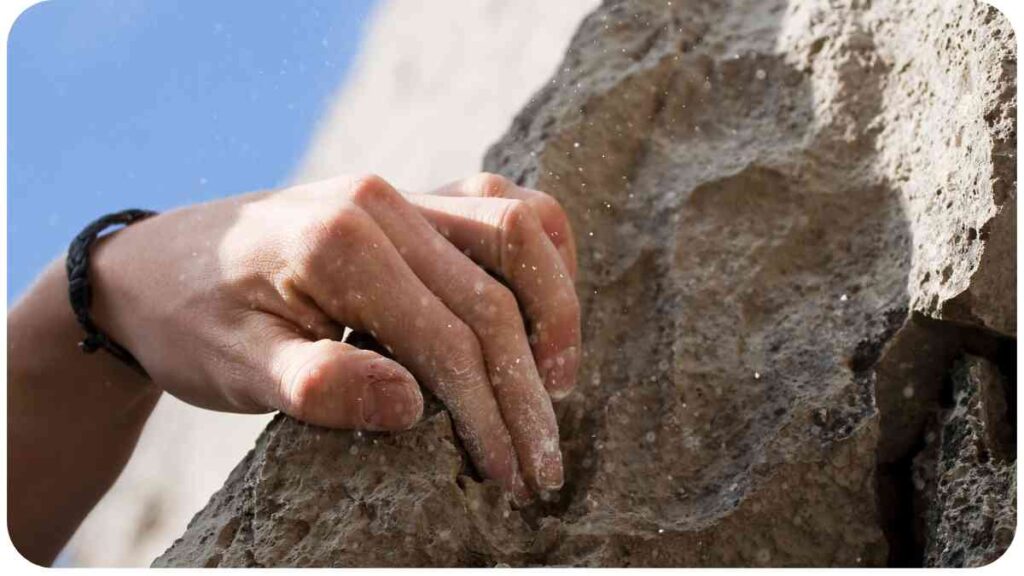 a person's hand is holding onto a rock wall