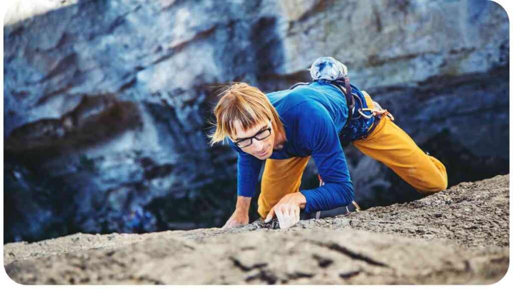 a person in glasses is climbing on a rock