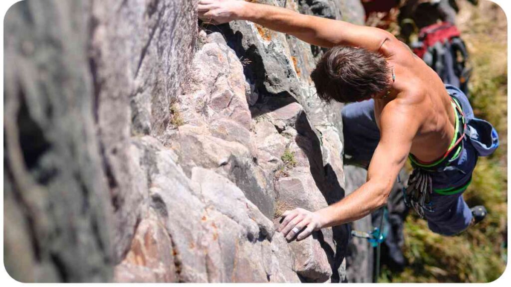 a person is climbing on a rock wall without a shirt.